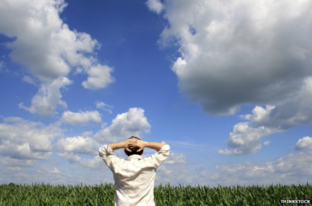 Man with hands behind head, staring at horizon