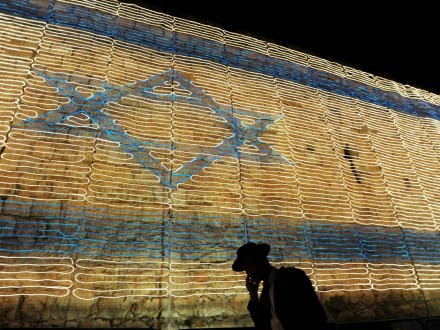 Es ist der 9. Mai 2011, der Unabhängigkeitstag in Israel und ein orthodoxer Jude mit Hut telefoniert und blickt dabei auf den Boden, im Hintergrund die israelische Flagge, bestehend aus Lichterketten in der alten Stadt Jerusalem. Sie feiern den 63. Geburtstag des Beginns eines jüdischen Staates. ( imago/UPI Photo)